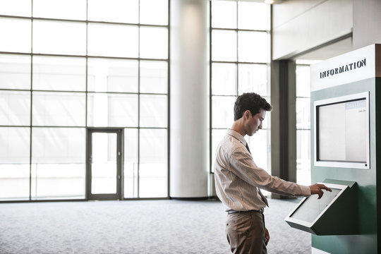 Businessman At Information Kiosk In Large Lobby Area