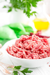 Forcemeat. Raw ground pork meat in bowl on white kitchen table. Fresh minced meat