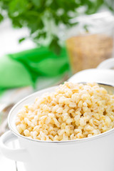 Bulgur wheat. Boiled bulgur cereal in pot on white kitchen table. Healthy vegetarian food
