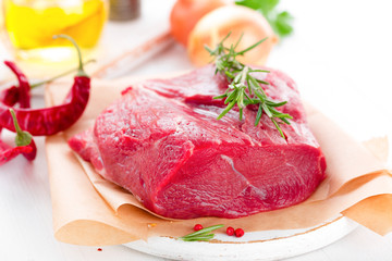 Raw beef meat tenderloin on white background with cooking ingredients closeup. Fresh beef meat on kitchen table