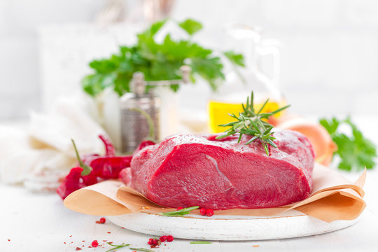 Raw beef meat tenderloin on white background with cooking ingredients closeup. Fresh beef meat on kitchen table