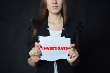 In the hands of a businessman a scrap of paper with the inscription:INVESTIGATE