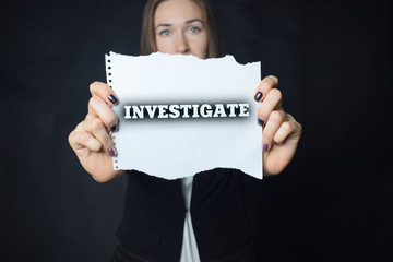 In the hands of a businessman a scrap of paper with the inscription:INVESTIGATE