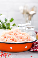 Forcemeat. Raw ground chicken meat in bowl on white kitchen table. Fresh minced chicken breast meat