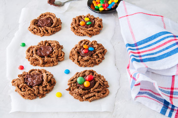 Chocolate bird's nest cookies decorated with colorful candies on a white background.