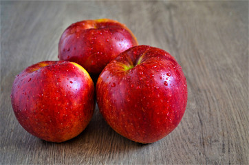 Fresh ripe apples with water drops on a wooden table.