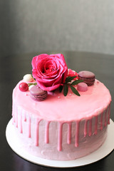 Tasty pink homemade cake decorated by rose and macarons