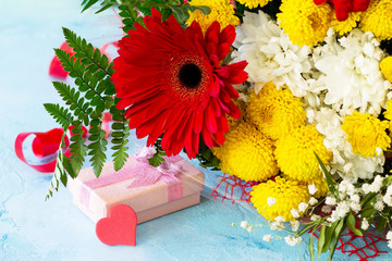 A wedding story or background Mother's Day. Basket bouquet of gerbera with chrysanthemums and present on a stone background or slate.