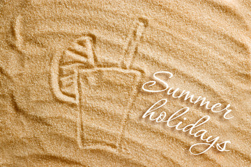 A glass of fresh juice is drawn on the sand and an inscription of summer holidays. Beach background. View from above. The concept of summer, summer kanikkuly, vacation, holydays.