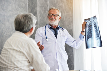 Male doctor and Asian patient are examining x-ray film together.