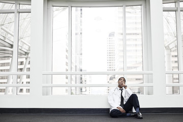Black man doctor stressed out and sitting on floor.