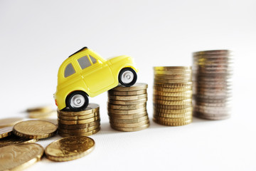 Rising cost for car running concept with miniature yellow car on stack of cash money

