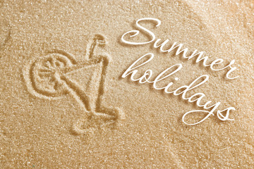 A glass of fresh juice is drawn on the sand and an inscription of summer holidays. Beach background. View from above. The concept of summer, summer kanikkuly, vacation, holydays.