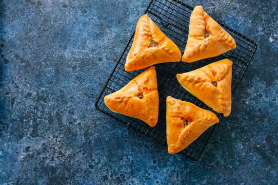 Homemade baked uchpuchmak (samsa) with meat and potato served on a wire rack on a blue sackcloth background. Top view and copy space.
