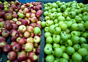 Fresh green and red apples lie in the shop window