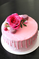 Tasty pink homemade cake decorated by rose and macarons