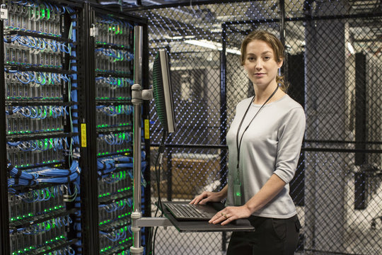 Caucasian woman technician working on computer servers in a server farm.