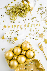 Golden Hashtag celebrating the happy easter, over a white background with golden star pallette and golden eggs box,whistle and a crystal champagne glass, luxury concept