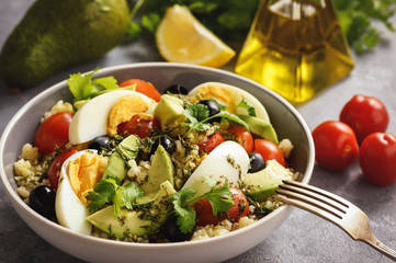 Bulgur salad with eggs, avocado, tomatoes and olives.
