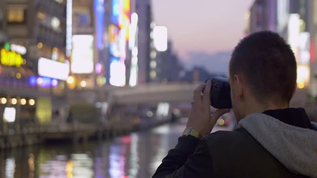 Tourist taking photos of neon lights in Osaka Japan.