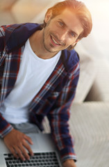 young man working on laptop and looking at camera. view from above