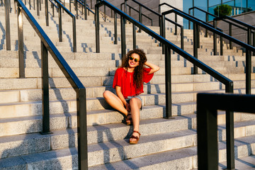 Happy woman posing at camera while sitting on steps, outdoors