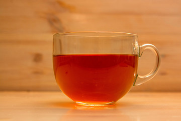 Transparent cup with tea on wooden background