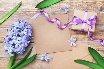 Mothers Day greeting card with kraft envelope and gift or present box decorated flowers on wooden vintage background. Top view.
