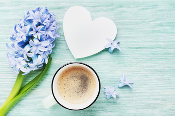 Mothers Day spring greeting background with hyacinth flowers, cup of coffee and white wooden heart top view. Holiday morning breakfast.