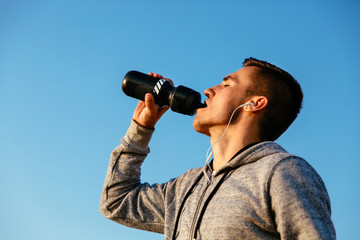 Fototapeta na wymiar Outdoor photo of guy drinking a water after training, outdoors