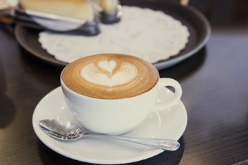 closeup hot coffee latte art cup on wood table.