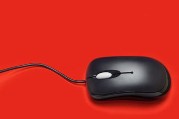 Computer mouse with wire on a red background.