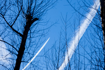 Condensation trace highlighted by the setting sun behind a twin-engine turbojet passenger plane in...