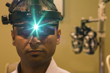 Ophthalmologist wearing a binocular indirect ophthalmoscope for examining eyes.