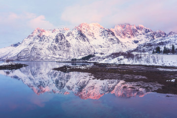 Fototapeta na wymiar Scenery winter landscape in the Norway. Mountain ridge with reflection in the lake in gentle sunset light, Laupstad, Lofoten Islands