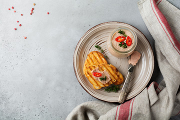 Chicken homemade pate from liver with red pepper, thyme twigs and toasted bread slices on wooden old board on gray concrete or stone background. Selective focus. Top view. Copy space.