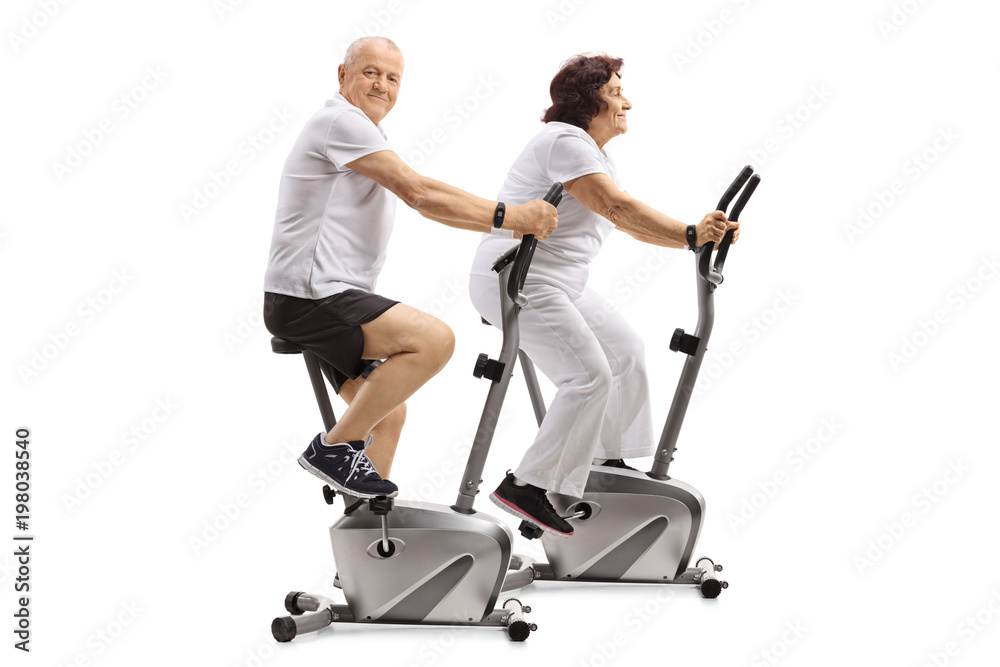 Poster Mature man and a mature woman exercising on stationary bikes