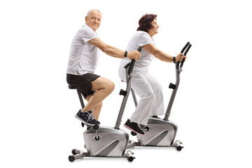 Mature man and a mature woman exercising on stationary bikes