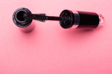 Eyelash makeup brush and mascara bottle close up on pink background with copyspace