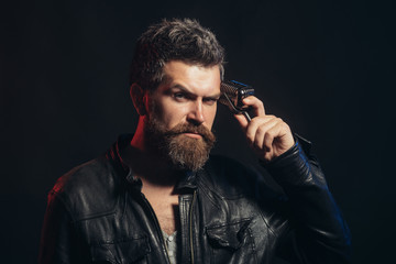 Male singer with old fashioned microphone. Concentrated bearded singer with microphone. Rock star man with long beard and mustache in black leather jacket holds microphone. Copy space for advertise.