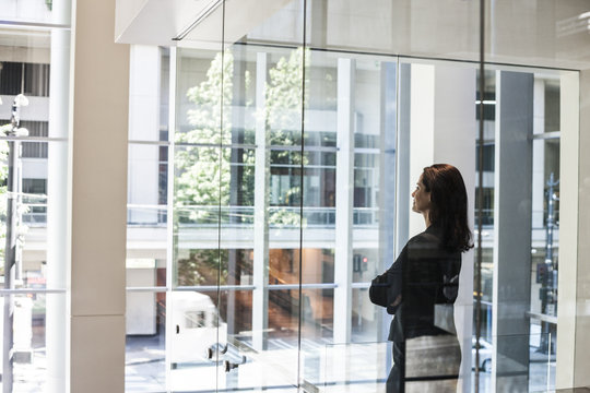 Businesswoman Standing In Conference Room Window In Large Business Center