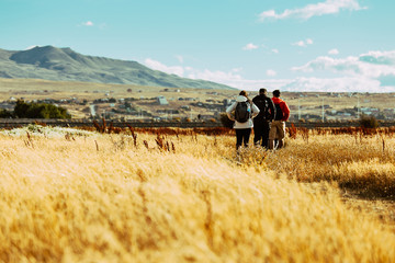 Group of people walking along path in high grassy fields during