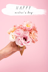 Fototapeta na wymiar Cropped shot of person holding waffle cone with beautiful blooming flowers isolated on pink