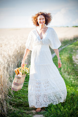 Pretty smiling Woman Outdoors with wicker bag with natural meal and flowers