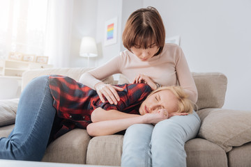 Personal problems. Sad cheerless young woman lying on her girlfriend laps and crying while suffering from depression