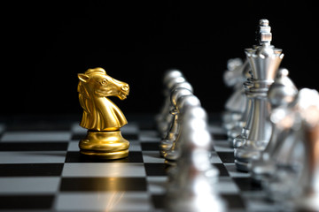 Gold horse in chess game face with the another silver team on black background (Concept for company strategy, business victory or decision)