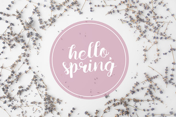 top view of HELLO SPRING lettering with round frame of lavender flowers on white tabletop
