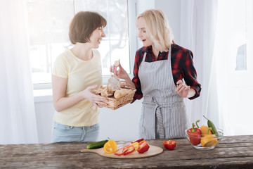 So delicious. Nice positive happy woman standing in the kitchen and tasting bread while preparing dinner