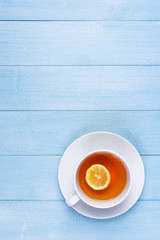 The cup of tea with lemon on the light-blue wooden table