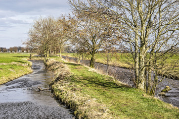Historic footpath between ditches and canals on the Tiendweg in the polder near the city of...